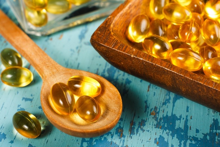 Cod liver oil capsules on a wooden spoon. © Getty Images