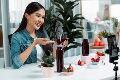 A woman promoting a juice product during a livestreaming session. © Getty Images